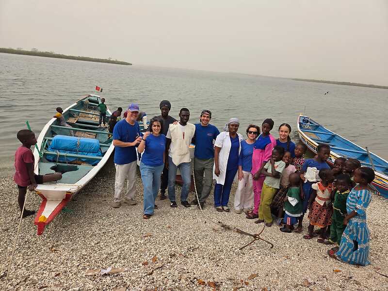 L'équipe de Médecins du Fleuve et les enfants du village devant les pirogues